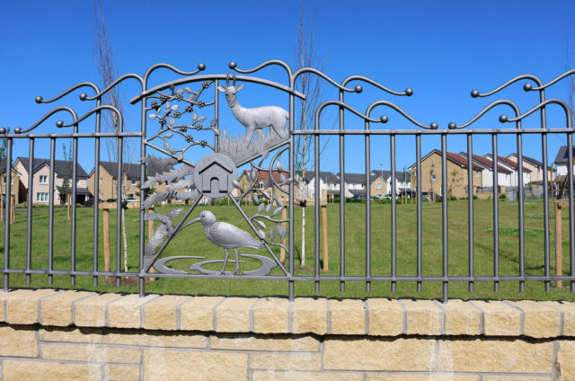 A forged steel panel with balustrade either side. The panels depicts brambles, a roe deer a Curlew, gorse and Beech leaves.