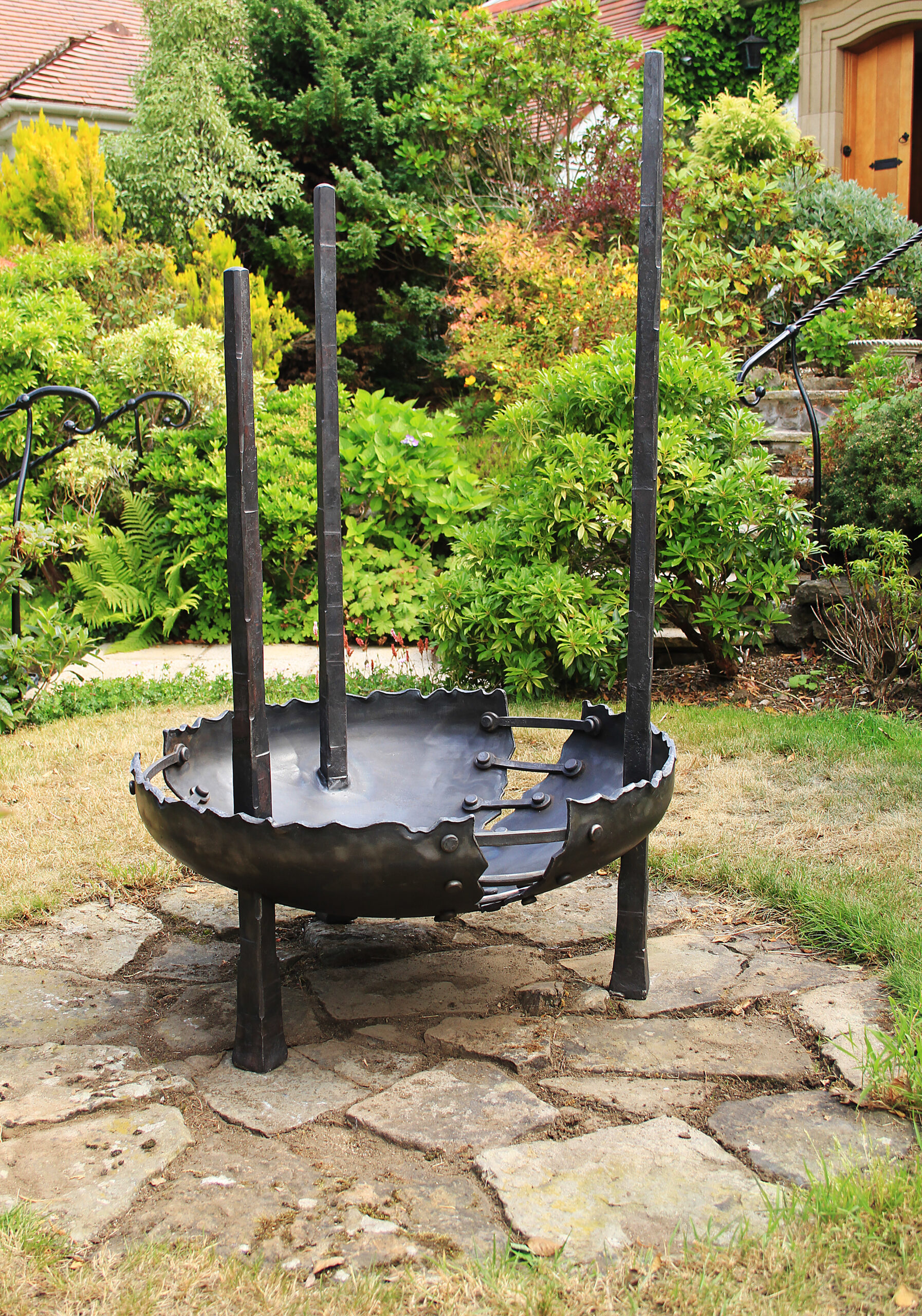 Three tall spires intersect through a large sculpted bowl to create a rugged fire pit for the garden. Designed and created by the Ratho Byres Forge artist blacksmith Shona Johnson & Pete Hill.